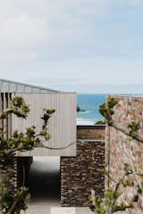 Exterior, Metal Roof Material, Wood Siding Material, House Building Type, Flat RoofLine, and Stone Siding Material Glimpse through building framing the ocean views.   Photo 7 of 18 in Green Hedges by Watershedd