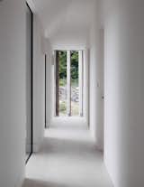 View down bedroom hallway looking through frameless window and privacy screens.