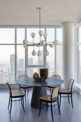 Dining Room, Chair, Ceiling Lighting, Table, and Porcelain Tile Floor Dining Room with Round Black Cerused Oak Dining Table, Cane Chairs, designed by Hive LA Home  Photo 8 of 25 in Love It or Hate It? Cane Furnishings by Dwell from Hill St High Rise Downtown LA