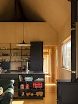 Kitchen, Metal Counter, Cooktops, Undermount Sink, Wood Counter, Range, Refrigerator, Metal Cabinet, Pendant Lighting, Microwave, Open Cabinet, Wood Backsplashe, Drop In Sink, Dishwasher, Plywood Floor, Wall Oven, Ceiling Lighting, and Light Hardwood Floor With a rustic wood-burning fireplace to match the sleek black steel kitchen, this family home is designed for the essentials of easy New Zealand farm life.   Photo 5 of 9 in Karangahake House by MAKE Architects 