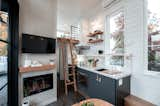 Kitchen, Stone Slab Backsplashe, Range Hood, Dishwasher, Cooktops, Recessed Lighting, Marble Counter, Dark Hardwood Floor, Undermount Sink, Wall Oven, Wall Lighting, Colorful Cabinet, and Accent Lighting Gooseneck Tiny home with dark cabinets, brass hardware, white faucet, porcelain counters, and floating shelves by Tru Form Tiny  Photo 2 of 25 in Innovating Space and Safety in the Face of Nature's Fury - This Build is FOR SALE NOW by Tru Form Tiny