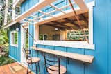 An outdoor deck and bar area with a mango wood counter and a massive window create an indoor/outdoor living experience.