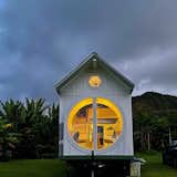 An owner send-in of the Oasis model tiny home all lit up on it's new property in Hana, Maui. a 6' round window always offers stunning jungle views
