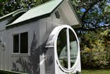 Exterior, Beach House Building Type, Curved RoofLine, Metal Roof Material, Gable RoofLine, Wood Siding Material, and A-Frame RoofLine Tiny Home with white exterior and green trim. Grey tropical  accents  Photo 4 of 37 in The 3rd Oasis Model ATU- Build by: paradisetinyhomes.com by elliekdesign.com