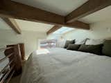 This tiny home has a king size bed up in the loft with exposed ceiling beams and ohia wood and copper railing. Linen bedding, 4 awning windows, and a ceiling fan keep things cool- though this unit is being kept at high elevation where staying warm is welcome. 