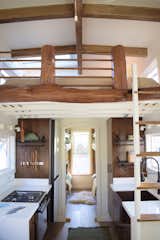 The ladder up to the sleeping loft with natural wood rungs gets tucked up behind the door when not in use and pulled out at an approachable angle when in use acting as a second security system. The loft railing and face are cuts from local Hawaiian Ohia that the owner provided towards the project. We were so excited to incorporate building materials they had.