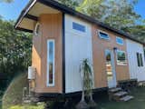 an outdoor shower mounted on the side of this ATU. It has a tub-fill so you could have an outdoor tub - perfect in Hawaii. Black white and wood exterior. 8x28' Paradise Model Tiny Home