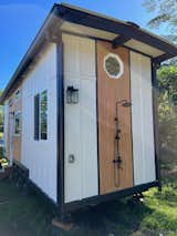 an outdoor shower mounted on the side of this ATU. It has a tub-fill so you could have an outdoor tub - perfect in Hawaii. Black white and wood exterior. 8x28' Paradise Model Tiny Home