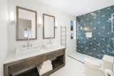 Echoing the primary bathroom, the guest bathroom features aquatic blue geometric tiles, marble, and wood.
