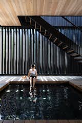 Hunter's son soaks his feet in the black-tiled spa under the stair that connects the upper dining deck to the ground level patio. Angled boards provide screening  but still let in light.