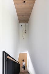 After playing with spheres, Bérubé commissioned Lindsey Adelman Studio to create a cylindrical pendant in black, yellow, walnut, and brass as a fun touch over the stairs. Bérubé designed the pared down oak pole handrail set into a metal support. "Our millworkers can customize anything,