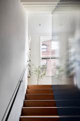 The stairs are hidden behind a core wood block with a high gloss finish for a mirror-like reflection. Fortuitously, there is a window at the top of each run. "They're not perfectly aligned, but they bring light down at every level,