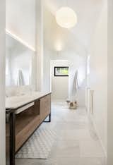 The primary bath on the first floor has a custom vanity and a randomly textured tile backsplash.