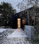 The home sits at the end of a quiet, gravel road just 325-yards from the ocean. A board-formed concrete wall along the entry path hints at what is indoors.