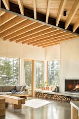 The living room’s woodburning fireplace has a concrete hearth that wraps the chimney and runs under the windows, acting as seating, a plant ledge, and a place to store logs.