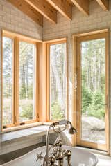 A freestanding slipper tub floats in the center of the primary bath, separated from the walk-in shower with a frameless glass panel that nearly reaches the ceiling. 