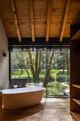 Bath Room, Wood Counter, Medium Hardwood Floor, Drop In Tub, Drop In Sink, Recessed Lighting, and Wall Lighting  Photo 11 of 14 in A Dramatic Hallway Forms the Spine of This Shou Sugi Ban Retreat in Mexico from L7 Home