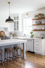 Classic, chic and sophisticated — the open kitchen features Big Chill's Classic Dishwasher in White with Brushed Brass trim and Big Chill's 36" Classic Stove in Custom Basalt Gray with Brushed Brass trim.