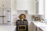 The elegant pairing of Big Chill's Classic Fridge in White with Satin Nickel trim and Big Chill's 36" Classic Stove in Custom Basalt Gray with Brushed Brass trim coordinates harmoniously in Kirsten Krason's kitchen.