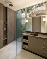 The shower features a floor-to-ceiling casement window that opens to an enclosed boulder courtyard, creating an outdoor shower experience.  The shower niche runs all the way to the floor with the drain at the base to keep the floor clear.