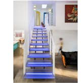 The show-stopping element of the renovation is the open steel stair with thick acrylic treads lit by multi-color LED lights.