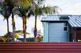 Iridescent corrugated metal defines the back volume of the house and a red corrugated metal wall surrounds the property.  The roof was replaced with standing metal seam panels.
