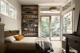 Bedroom, Bed, Ceiling Lighting, Shelves, Light Hardwood Floor, and Bookcase The primary bedroom suite extends to an outdoor deck tucked amongst the redwoods.  Photo 3 of 16 in Modern Cottage by Richardson Pribuss Architects