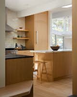 In the kitchen, absolute black countertops are set against a white Carrara marble kitchen island and tied together with subtle oak cabinetry and pearlescent organic tile work.