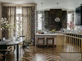 Dining Area + Kitchen: the open floor plan on the primary floor of the residence showcases JKA’s signature blend of eras and styles, an eclectic mix of Modern gestures, Classical elements, and luxurious materials and details like the custom brass stair rail.