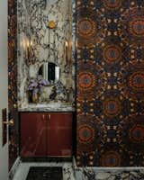 This Powder Room might be the smallest space in the home, but it may very well make the biggest, boldest statement of them all with its blood-red custom vanity, Damien Hirst Butterfly Kaleidoscope wallpaper, and stunning Keystone Prunella slab marble countertop.