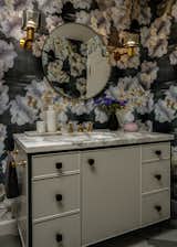 Visitors of the Guest Bath are treated to a custom vanity topped with Calacatta Oro marble and dark linen textured wallpaper with sumptuous floral motifs.