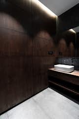 Wood panelled wall and raw Indian granite floor in the toilet