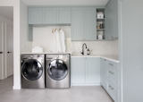 In the laundry room, serene cabinets in Wedgewood Grey by Benjamin Moore make this active, crucial space feel airy and bright.