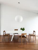 Dining Room, Ceiling Lighting, Table, Chair, Medium Hardwood Floor, and Pendant Lighting  Photo 8 of 25 in Black Pivot Doors Frame Views of This Australian Home’s Verdant Garden
