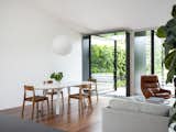 Dining Room, Ceiling Lighting, Pendant Lighting, Medium Hardwood Floor, Chair, and Table  Photos from Black Pivot Doors Frame Views of This Australian Home’s Verdant Garden