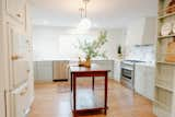 Kitchen, Range Hood, Marble Counter, Medium Hardwood Floor, Wood Cabinet, Pendant Lighting, White Cabinet, Refrigerator, Recessed Lighting, Range, Dishwasher, and Colorful Cabinet  Photo 1 of 6 in Cozy Cottage in North Carolina by Kendis Charles