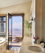 Both the tiramisu travertine on the bathroom’s shower walls and the milky cream cabinets in the bathroom offset the home’s rustic style with a refreshing airiness.