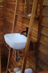The structure’s simple construction is laid bare with the vanity: wood frame holds up the vessel sink and provides a place to store towels below.