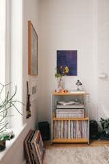 Each corner provided the artist couple a chance to set a scene.  In this media space, the tone is set by the vintage silver turntable, a hand me down from Timothy's father, and by the record collection, many from Maureen's father.  Maureen finished the look with a contrastingly dark blue painting and a delicately simple bouquet. 

The record shelf is from Modernica's "Case Study" furniture series.   Photo 14 of 28 in My House: A Brooklyn Couple’s 1800s Townhome Melds Eras, Heirlooms, and Artwork