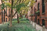 The home is one of 34 identical workers’ cottages lining a lush central courtyard. Cloistered from street traffic by iron gates at either end, the row houses feature paired arched doorways under Gothic gables, decorative brickwork, and delicate wrought iron over windows and doors.  