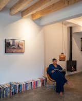 Beneath a photograph by Iwan Baan, Christine's books become a part of the gallery wall.  Here, she sits in one of their two Arne Jacobsen swan chairs beside a crocheted lamp of her own design. The hanging stove is from Leenders.