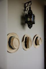 In a home with minimal decoration, every item bears its weight in creating a holistic style: here the light fixture and the row of (very necessary) fedoras contrast and complement each other.  Photo 22 of 24 in My House: Nadav Kander’s Ibiza Retreat Is Worlds Away From the Island’s Oonzt-Oonzt Nightlife