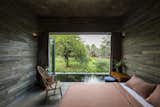 Bedroom, Bed, Chair, Concrete Floor, Ceiling Lighting, and Pendant Lighting  Photo 11 of 16 in A Koi-Filled Moat Surrounds This Vietnamese House from Am house