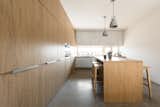 Kitchen, Laminate Cabinet, Wall Oven, Dishwasher, Cooktops, Range Hood, Ceiling Lighting, Pendant Lighting, Concrete Floor, Wood Backsplashe, Laminate Counter, Refrigerator, Undermount Sink, Wood Counter, and Wood Cabinet  Photo 4 of 28 in House with a wallnut grove by Konkrét Stúdió