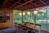 The combined living/dining room features globe pendant lights, slate floors, redwood walls and floor to ceiling windows.