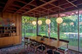 The combined living/dining room features globe pendant lights, slate floors, redwood walls and floor to ceiling windows.