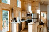 Kitchen, Wood Counter, Refrigerator, Wall Oven, Light Hardwood Floor, Wood Cabinet, Cooktops, Microwave, and Drop In Sink Kitchen with floor to ceiling windows  Photo 7 of 32 in gatHER indie treehouse by Nikki McCall