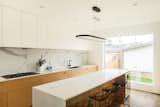 Kitchen, Engineered Quartz Counter, Cooktops, Undermount Sink, White Cabinet, Porcelain Tile Backsplashe, Light Hardwood Floor, Wood Cabinet, and Pendant Lighting Kitchen Island  Photo 13 of 42 in Pop goes the Young by Joanne Madeo
