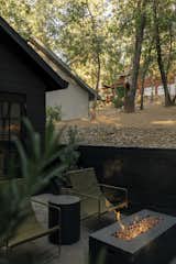 In front of the workshop is a campfire style setting area complete with <span style="font-family: Theinhardt, -apple-system, BlinkMacSystemFont, &quot;Segoe UI&quot;, Roboto, Oxygen-Sans, Ubuntu, Cantarell, &quot;Helvetica Neue&quot;, sans-serif;">Ferm Living Desert lounge chairs, Fat Boy Bolleke globe lamps, and a concrete gas fire pit.</span>  Photo 7 of 10 in Furniture by Laramie from Budget Breakdown: A Bay Area Couple Turn an A-Frame Cabin Near Yosemite Into a $600-a-Night Rental