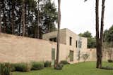 The curved outer wall connects the main residence to a two-story guest house perched on the forest's edge. 